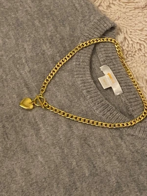 Guldigt halsband med hjärthänge - Snyggt halsband i guldfärgad rostfritt stål med en chunky kedja och ett hjärthänge. Halsbandet har en toggle-låsning som ger en trendig touch. Perfekt accessoar för att lyfta vilken outfit som helst. Inget synligt märke på halsbandet.