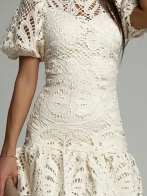 Vit spetsklänning med puffärm - Superfin vit kortklänning i spets med puffärmar och rund hals. Klänningen har ett vackert spetsmönster och volang nedtill för en romantisk vibe. Perfekt till student eller sommarens alla tillfällen! Klänningen är originellt en L och sen insydd till en M 