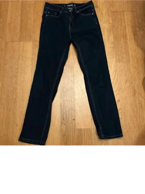 Mörkblå raka jeans från Denim 1953 - Säljer ett par mörkblå jeans från Denim 1953, modell alice. Jeansen har raka ben, klassisk femficksdesign och kontrastsömmar. Tillverkade i ett slitstarkt denimtyg med dragkedjegylf och knapp i midjan. Perfekta för en clean och tidlös look.