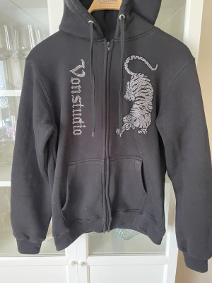 Svart Zip-hoodie, Vonstudio - Sjukt snygg svart Zip-hoodie från Vonstudio med pärlor, i väldigt bra skick. Vad jag kan se sitter alla pärlor kvar.  Storlek L, jag skulle säga att den är lite tajtare så passar M med. Ny pris: 999kr, mitt pris: 529kr