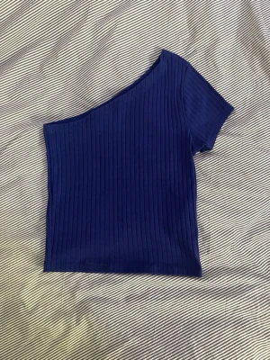 Marinblå ribbad oneshoulder topp - Snygg marinblå topp med ribbad struktur och oneshoulder-design. Kortärmad och figurnära passform, perfekt för att lyfta din outfit med en trendig touch.