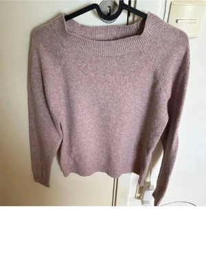 Stickad tröja vero Moda - En enkel och snygg ljuslila stickad tröja med bred ribbad krage och långa ärmar. Tröjan har ribbstickade muddar vid ärmslut och nederkant. Perfekt för att hålla sig varm under kyliga dagar. Materialet ser ut att vara mjukt och skönt.