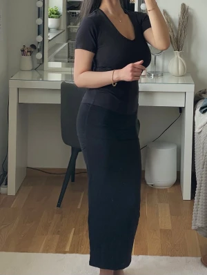 Svart kjol från Gina Tricot - Svart långkjol från Gina Tricot. Tight passform med rynkade detaljer på sidorna. Tillverkad i mjukt, stretchigt material som sitter snyggt. Passar både till vardag och festliga tillfällen. Endast använd några gånger.