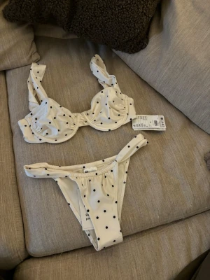 Hm bikini - Superfin bikini från Zara i vit med svarta prickar. Överdelen har bygel och breda axelband, medan underdelen är klassisk med hög benskärning. Perfekt för strandhäng och poolparty. Materialet är mjukt och stretchigt syntet. Endast testat! Ny med prislapp!! 💞💞