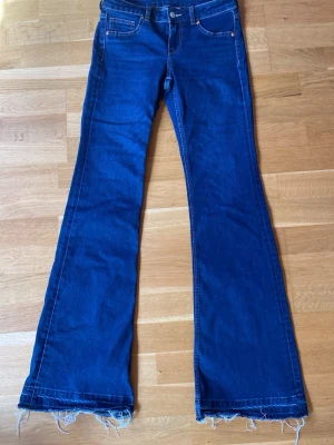 Blå bootcut jeans - Säljer ett par blå bootcut jeans med fransig kant. 