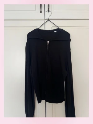 Svart hoodie med dragkedja - 💓En svart hoodie med dragkedja framtill och huva. Modellen är rak med långa ärmar och ribbade muddar. Perfekt för en chill och avslappnad stil. Materialet ser ut att vara mjukt och stretchigt, vilket gör den skön att bära. köpt från Gina trikot 💗L-XL storlek