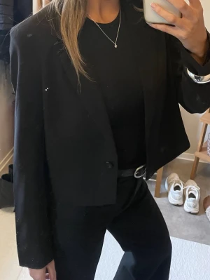 Kort svart kavaj i klassisk modell - Snygg svart kavaj med croppad passform och enkelknäppning. Passar även för någon som har storlek xs/s