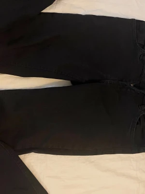 Svarta flare jeans - Säljer ett par svarta jeans. klassisk femficksdesign. Jeansen har låg midja och är tillverkade i ett mjukt denimtyg som ger en clean och stilren look. Perfekta till en avslappnad outfit och enkla att matcha med olika stilar.