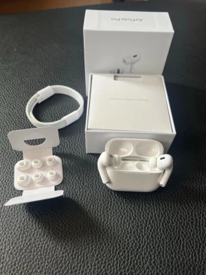 Apple AirPods Pro med laddningsetui - Säljer ett par vita Apple AirPods Pro med trådlöst laddningsetui. Inkluderar originalkartong, laddningskabel och extra silikonpluggar i olika storlekar. Snygg och kompakt design i plast, perfekt för dig som vill ha grymt ljud och smidig anslutning till din iPhone.