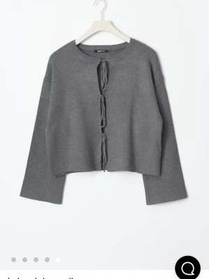Grå stickad cardigan med knytband//kostar egentligen 400kr//säljer en också i vit - Trendig grå stickad cardigan från Monki med avslappnad passform och vida ärmar. Öppen framtill med tre knytband som stängning ger en cool och modern look. Perfekt att slänga över en topp för en chill vibe. Materialet är mjukt och stretchigt.