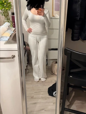 Vit långärmad tröja med rund hals - Säljer en vit långärmad tröja med rund hals och figurnära passform. Tröjan har en enkel och stilren design som passar perfekt till både jeans och mjukisbyxor. Materialet ser mjukt och stretchigt ut för extra komfort. 