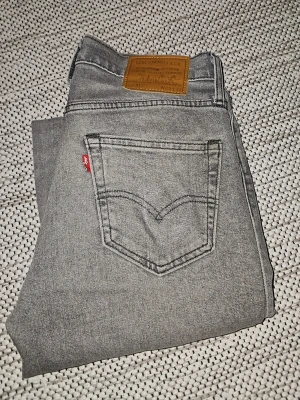 Grå Levi's jeans med rak passform - Säljer ett par grå jeans från Levi's med klassisk rak passform och femficksmodell. Jeansen har den ikoniska läderpatchen bak i midjan och den röda Levi's-taggen på bakfickan. Tillverkade i mjukt denimtyg som ger en avslappnad look. Är öppen för prisförslag vid snabb försäljning. Köpta för 1299 på Best of Brands 2024 men knappt använda.
