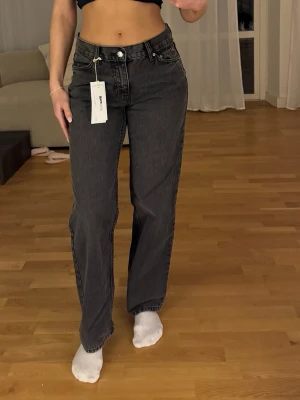 Grå jeans  - Grå jeans med prislapp kvar. Från Gina Tricot i storlek 34. Dock har jag gjort två små hål (se bild) för att dra igenom ett snöre runt midjan och kunna tajta till dom så de inte sticker ut vid svanken. Hålen syns inte, men några av snörerna på lappen där bak (se bild) har åkt ur men inget syns mycket. Det kom aldrig till användning ändå, endast testade med prislappen kvar. Jag är 160 cm 