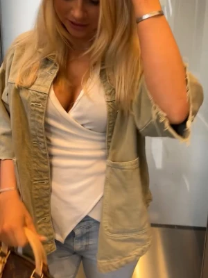 Grön Zara jacka - Stilren beige overshirt med stora framfickor och knappstängning. Jackan har en avslappnad passform och är tillverkad i ett mjukt, lite kraftigare bomullstyg. Perfekt att slänga över en t-shirt för en avslappnad look.