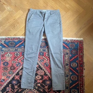 Grå chinos från Dondup - Snygga grå chinos från Dondup med smal passform och klassiska sidfickor. Byxorna har dragkedjegylf och knapp framtill. Byxorna är i riktigt bra skick!