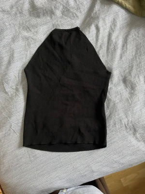Svart ribbad snörningstopp - Säljer en svart ribbad topp med snörning i ryggen. Stretchigt material.