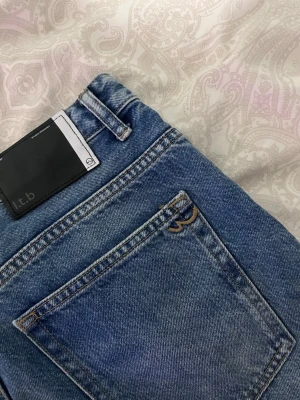 Blå raka jeans från L.T.B - Säljer ett par klassiska blå jeans från l.t.b med rak passform och hög midja. Jeansen har fem fickor, bälteshällor och en snygg tvättad look. Materialet är kraftig denim i bomull. Perfekta till en avslappnad stil.