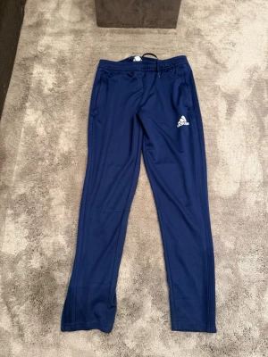Blå träningsbyxor från Adidas - Mörkblå träningsbyxor från Adidas. Grymt skick!