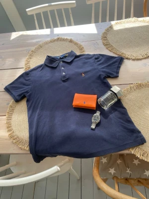 Marinblå pikéskjorta från Polo Ralph Lauren - Tja! Jag säljer nu denna freacha pikéskjortan från Polo Ralph Lauren. Skjortan är i storlek S och sitter slim. Skick: 8,5-9/10, riktigt skönt material (bomull). Perfekt till sommaren. Givetvis äkta! Hör av er ifall ni undrar något.