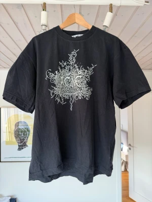 Svart t-shirt med grafiskt tryck - bekväm acne studios t-shirt. lite oversized och trycket lyser i mörkret