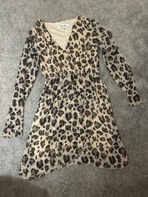 Leopardmönstrad omlottklänning Dry Lake - Säljer en snygg leopardmönstrad kortklänning från Dry Lake. Klänningen har omlottmodell med v-ringning, långa ärmar och resår i midjan.