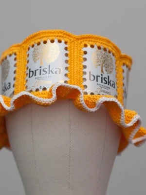 Virkad ölhatt Briska cider - Unik virkad ölhatt med Briska.  Virkad i 100% bomull. Passar upp till 60cm.  Vissa burkar kan ha mindre repor eller bucklor, vilket tyvärr kan uppstå under tillverkningen av hattarna. Insidan av burkarna slipas efter hålen tagits för att undvika vassa kanter. Därför kan det ibland finnas lite slipmärken, men det är inget som stör eftersom det är på insidan av hattarna.  Färger kan variera något beroende på skärminställningar.