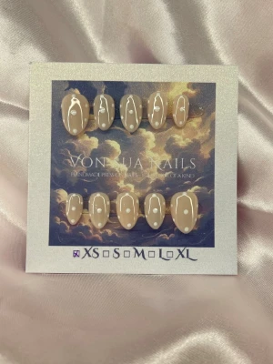 Milkie (XS);ExtraShortAlmond  - Snygga handgjorda press-on nagla i en nude nyans med vita prickar. Naglarna har en extra kort oval form och en glansig finish som ger en trendig look. Perfekt för dig som vill ha unika och stilrena naglar utan att gå till salong.XS: 14 mm, 11 mm, 11,5 mm, 10 mm, 8 mm