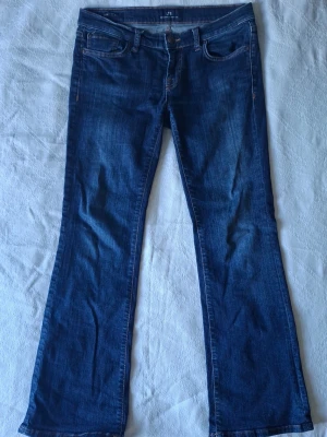 Mörkblå bootcut jeans - Säljer ett par mörkblå bootcut jeans med klassisk femficksdesign och snygga kontrastsömmar. Jeansen har en något utsvängd passform nedtill och är tillverkade i mjukt denimtyg. Perfekta för dig som gillar en tidlös och avslappnad stil.