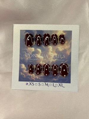 DarkRedDot (XS);ExtraShortOval  - Snygga handgjorda press-on naglar i en djup vinröd färg med vita prickar som dekoration. Naglarna har en extra kort oval form och är tillverkade i XS: 14 mm, 11 mm, 11,5 mm, 10 mm, 8 mm. Perfekt för dig som vill ha en unik och trendig nagelstil.
