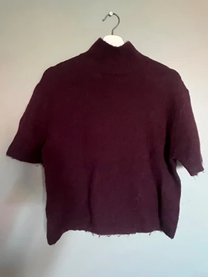 Vinröd stickad topp från Gina Tricot - Mysig vinröd stickad topp från Gina Tricot i ullblandning. Modellen har korta ärmar och hög hals. Helt ny, använd en gång! 💕☺️