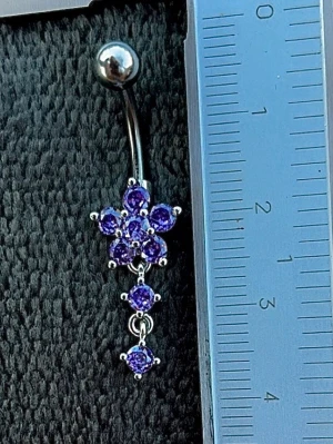 NY oanvänd Navelpiercing med hänge | Kirurgiskt stål | Blomma och lila stenar  - 💕30% Bundle-rabatt vid köp av minst 2 artiklar. ⭐️NY oanvänd piercing i kirurgiskt stål; rostfritt och säkert för läkta piercingar.                               📏MÅTT ⭕️Stavens längd: 10mm ⭕️Stavens tjocklek: 1,6mm ⭕️Smyckets totala längd: 35mm                                                                         🤍Färger: Silver och lila                                                          💌Skickas spårbart via Plick SafePay.