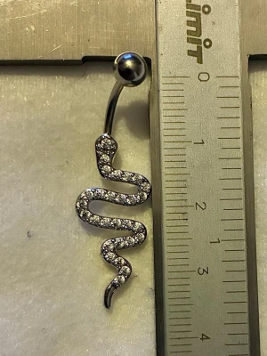 NY oanvänd Navelpiercing | Kirurgiskt stål | Orm och vita stenar  - 💕30% Bundle-rabatt vid köp av minst 2 artiklar. ⭐️NY oanvänd piercing i kirurgiskt stål; rostfritt och säkert för läkta piercingar.                               📏MÅTT ⭕️Stavens längd: 10mm ⭕️Stavens tjocklek: 1,6mm ⭕️Smyckets totala längd: 40mm                                                                         🤍Färger: Silver och vit                                                            💌Skickas spårbart via Plick SafePay.