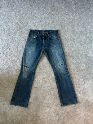 Blåa Levis 527 Bootcut Vintage Jeans Storlek W32 L32 - Mycket fina Levis jeans i blå färg | Jeansen är i mycket bra skick och sparsamt använda. |  Äkta som allt annat jag säljer! ✅ |  Storlek: W32 | Skick: Mycket Bra Skick - har tyvärr en del väldigt små fläckar o blivit lagade på ett ställe (SE SISTA BILD) | Färg: Blå | Märke: Levis Modell: Jeans |   Hör gärna av dig vid frågor så svarar jag så fort jag kan! 😁 |  (SKU - 187)