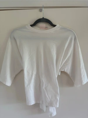 Vit topp med knyt i ryggen - Säljer en vit topp från Nelly med halvlånga ärmar och snygg knytning i ryggen. Perfekt till jeans eller kjol för en chill och trendig look.