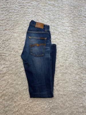 Mörkblå Nudie Grim Tim  - Skick: 10/10, nästan oanvända| Storlek: W27 L32| Modell Grim Tim vilket är straight/slimfit| Gåva ingår vid köp!