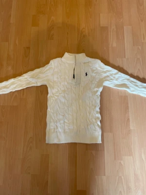 Vit kabelstickad tröja Polo Ralph Lauren - Kabelstickad vit tröja från Polo Ralph Lauren med halv dragkedja och hög krage. Tröjan är mer som en L istället för en XXL. Aldrig använd säljer för det var fel passform😃