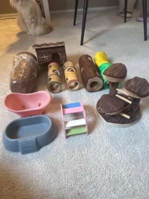 Tillbehörspaket för smådjur - Säljer ett paket med tillbehör för smådjur som hamster (!!!!dvärghamster!!!). Innehåller tunnlar i trä och plast, ett litet hus i trä, färgglada leksaker,  liten stege i trä med färgade steg. Perfekt för att skapa en rolig och stimulerande miljö.