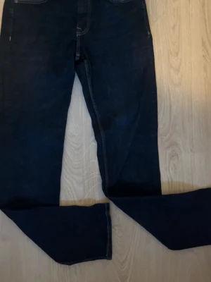 Mörkblå skinny jeans - Säljer ett par mörkblå skinny jeans med klassisk femficksdesign och smal passform. Jeansen har diskreta sömmar och är tillverkade i stretchigt denimtyg för extra komfort. Perfekta för en avslappnad och trendig look. Slim fit där de ska vara, helt nya som synts. 
