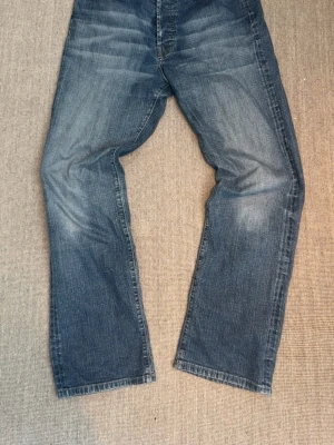 Diesel industry herr jeans - Säljer ett par klassiska blå jeans med raka ben och snygga tvättade detaljer. Jeansen har fem fickor och normal midja. Materialet är slitstark denim i bomull. Perfekta för en avslappnad och trendig stil.