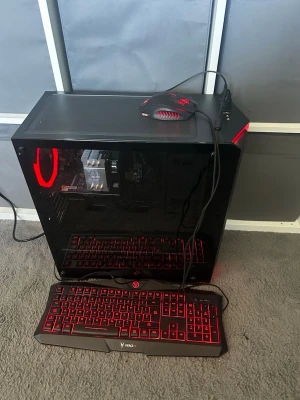 Svart gamingdator med röd LED-belysning - Säljer en stationär gamingdator med svart chassi och genomskinlig sidopanel. Datorn har röd LED-belysning, synlig kylare från Cooler Master och ett GeForce GTX-grafikkort. Medföljer svart tangentbord och mus med röd bakgrundsbelysning. Perfekt för gaming och vardagsbruk.