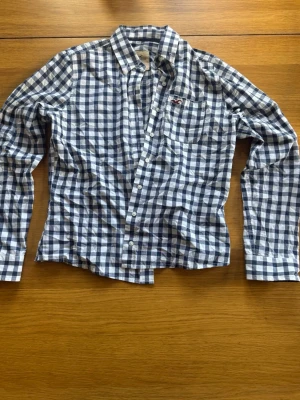 Hollister skjorta  - Säljer en klassisk rutig skjorta från Hollister i blått och vitt | lite tight M |  Tillverkad i mjuk bomull och perfekt för en avslappnad stil.