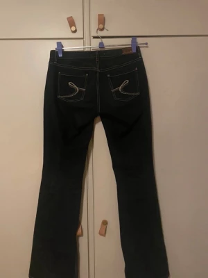 Low waist bootcut hilfiger denim - Säljer mina svarta lågmidjade bootcut jeans från Tommy Hilfiger. Köpte de på Vinted och har själv bara haft på mig de en gång men de var använda tidigare. Säker de p.g.a. de är för tajta i höften för att jag ska tycka att de är bekväma. Jag har strl. M i vanliga fall och kan ha på mig de, men de sitter som sagt ganska tajt så skulle säga att de passar en S bättre💕 Upptrampade vid fötterna (sista bilden) men inget som märks av när man har på sig de😊 Övriga byxan är i jättefint skick!