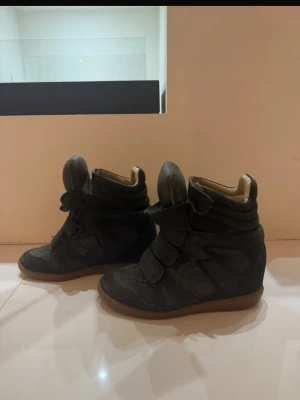 Isabel Marant svarta wedge sneakers - Svarta wedge sneakers från Isabel Marant med högt skaft och kardborreband. Skorna har en chunky sula i gummi och ovandel i mocka och läder. Insidan är ljusbeige och designen är ikonisk med extra vadderad plös.