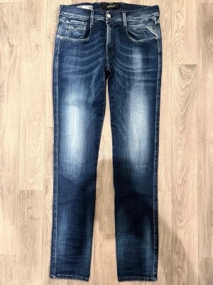Replay Anbass Hyperflex White Shades Fade Jeans Mörkblå W31/L34 - Slim Fit - Replay Anbass Hyperflex mörkblå jeans i stretchig Hyperflex denim med slim fit passform som sitter snyggt och bekvämt och funkar till allt, storlek W31/L34, midja 38,5 cm, ytterbenslängd 107 cm, benöppning 15 cm, modellen är 185cm & väger 65kg, i fint skick.