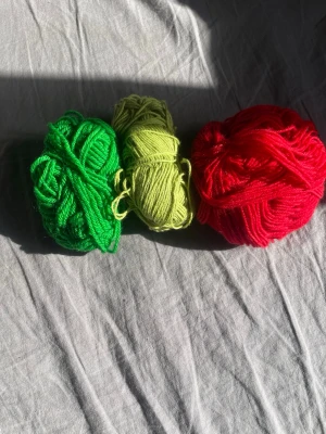 Garnnystan i grönt, gult och rött - Tre garnnystan i olika färger: ett grönt, ett ljusgult och ett rött. Perfekt för dig som gillar att sticka eller virka och vill ha färgglada projekt. Garnet är mjukt och passar till många olika DIY-projekt.
