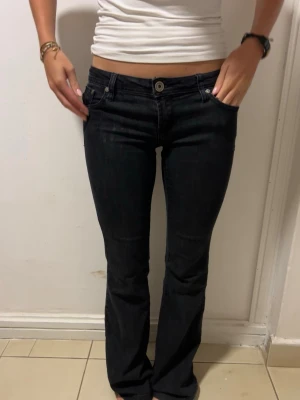 Vintage låg midjade jeans  - Säljer ett par mörkgråa/svarta  bootcut jeans med låg midja. Jeansen har en snygg passform som sitter tight upptill och släpper ut vid benen. Jeansen är i perfekt skick då de inte är slitna alls och knappt använda. Jag är 162cm och är lite för långa för mig, men annars sitter dem som en smäck! 