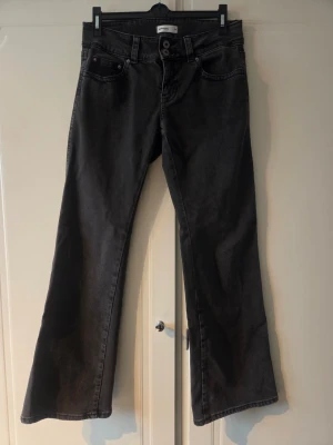 Svarta bootcut jeans från Perfect jeans - Säljer ett par svarta bootcut jeans från Perfect jeans. Jeansen har klassisk femficksdesign fram och två fickor med lock bak. Materialet är mjukt denim och passformen är utsvängd nedtill för en snygg siluett. Svart/grå färg. 