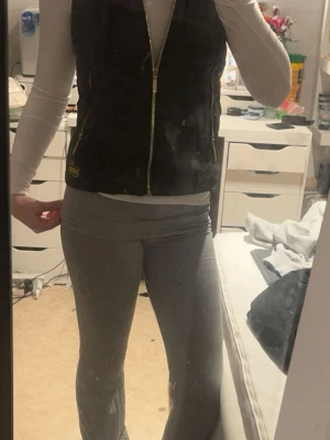 Svart dunväst från Barbour - Snygg svart dunväst från Barbour med guldfärgade dragkedjor och två fickor framtill. Västen har en quiltad design och en mjuk krage med fuskpäls. Perfekt att slänga över en hoodie eller långärmad tröja för en chill look. Storlek L i barn storlek men passar mig som e storlek xs i vuxen kläder 