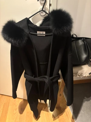 Kappa med päls   - Fin kappa från FUR Stockholm med stor pälskrage. Storlek S.