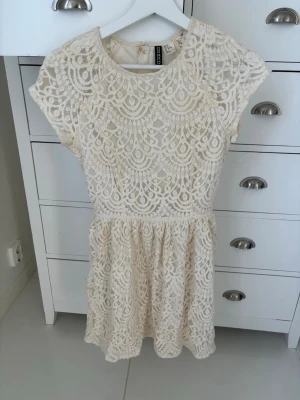 Vit spetsklänning från H&M - Säljer en söt vit kortklänning från H&M med vackert spetsmönster och rund halsringning. Klänningen har korta ärmar och dragkedja i ryggen. Perfekt för sommarens alla tillfällen! Storleken passar mer som en 34 